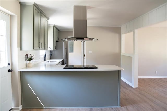 kitchen featuring island exhaust hood, black electric stovetop, light countertops, and a sink