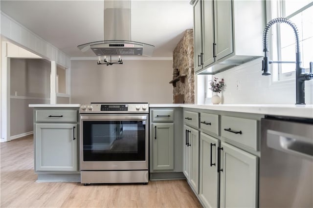 kitchen featuring decorative backsplash, appliances with stainless steel finishes, light countertops, and island range hood