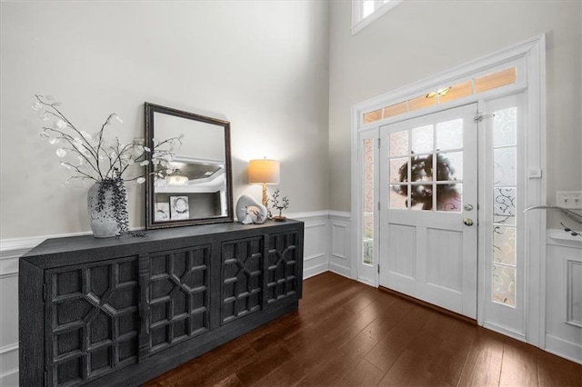 entrance foyer with a decorative wall, dark wood finished floors, and wainscoting