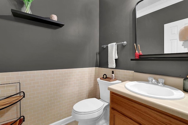 bathroom with vanity, toilet, ornamental molding, and tile walls