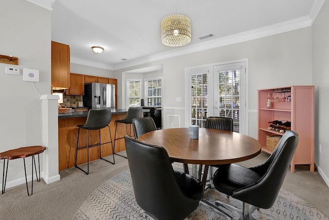 dining area with ornamental molding and light carpet