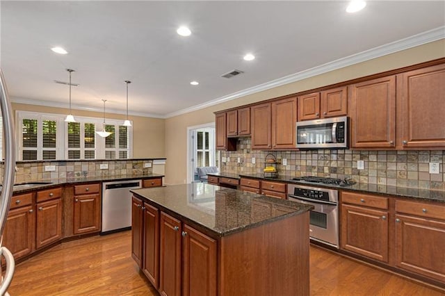 1725 Lynwood Pl, Alpharetta, GA 30004 - kitchen with appliances with stainless steel finishes, a kitchen island, decorative backsplash, wood finished floors, and brown cabinets