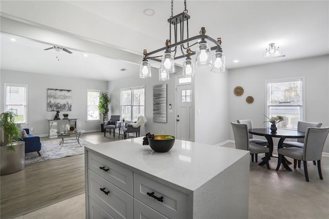 kitchen featuring baseboards, beamed ceiling, a ceiling fan, and open floor plan