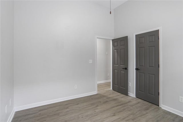 unfurnished bedroom featuring baseboards, lofted ceiling, and wood finished floors
