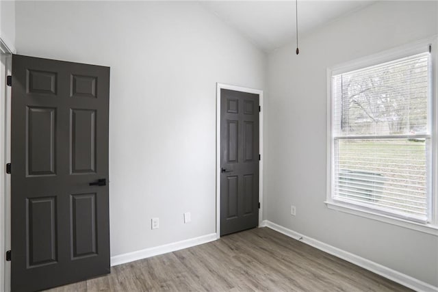 unfurnished bedroom with baseboards, lofted ceiling, and wood finished floors