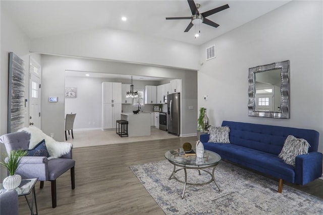 living area with light wood finished floors, lofted ceiling, baseboards, ceiling fan with notable chandelier, and visible vents