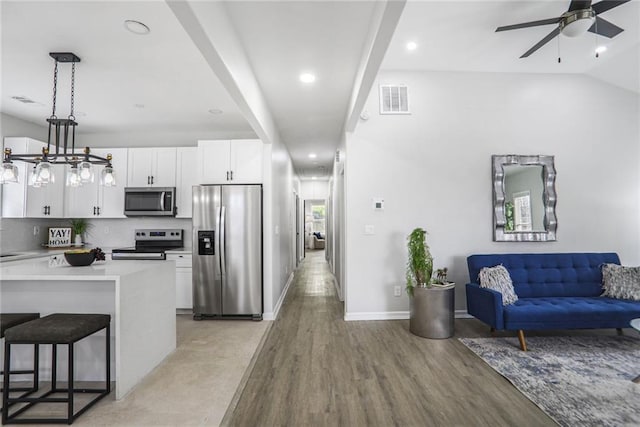 kitchen with a ceiling fan, open floor plan, stainless steel appliances, visible vents, and white cabinets