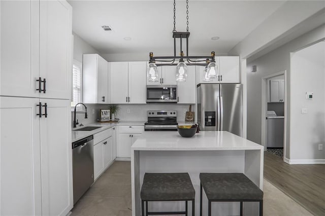 kitchen with a kitchen breakfast bar, stainless steel appliances, a center island, a sink, and washer / dryer