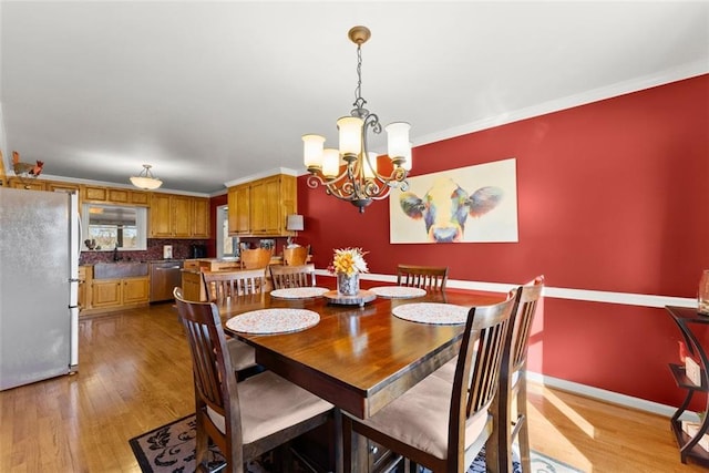 dining space with light wood-style flooring, baseboards, a chandelier, and crown molding