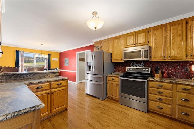 kitchen featuring dark countertops, appliances with stainless steel finishes, brown cabinetry, and hanging light fixtures