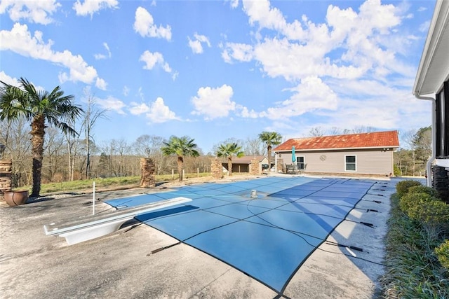 view of swimming pool with a patio area, a covered pool, and an outbuilding