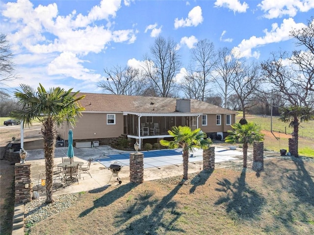 rear view of property featuring a sunroom, a patio area, and a yard