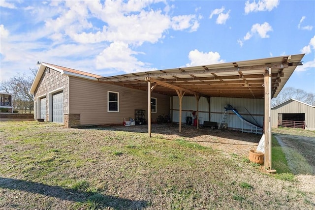 rear view of house with a garage, an outbuilding, and a yard