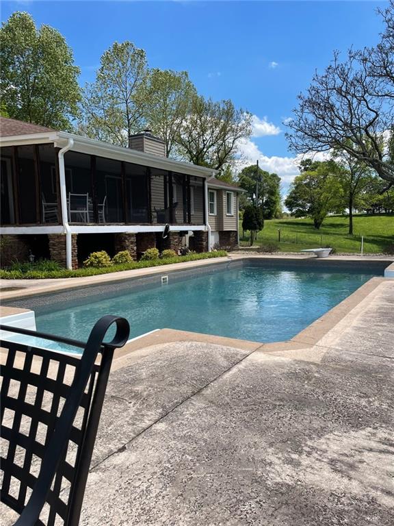 outdoor pool with a sunroom and a diving board