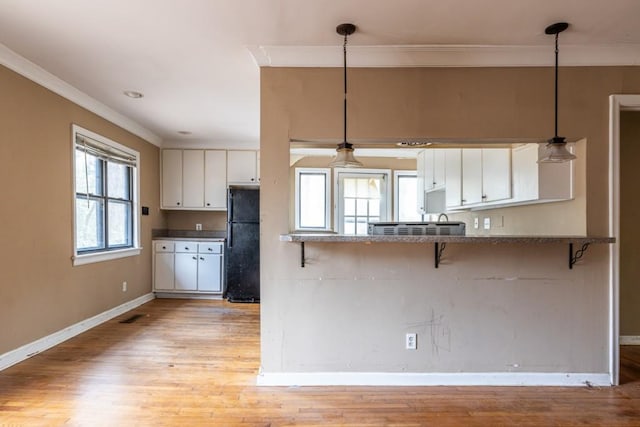 kitchen featuring black refrigerator, decorative light fixtures, kitchen peninsula, and white cabinets