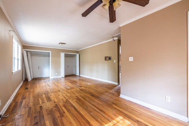 unfurnished bedroom with hardwood / wood-style flooring, crown molding, two closets, and ceiling fan