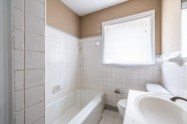 bathroom with tile patterned floors, toilet, sink, and tile walls