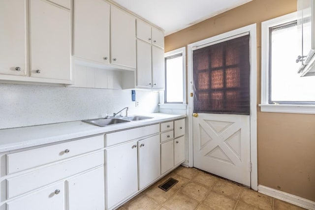 kitchen featuring tasteful backsplash, sink, and white cabinets