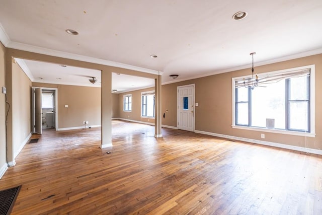 unfurnished room featuring hardwood / wood-style flooring, ornamental molding, and an inviting chandelier