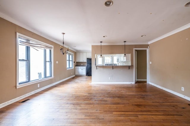 unfurnished living room featuring crown molding and hardwood / wood-style floors