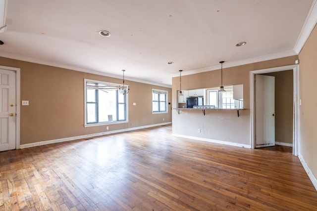 unfurnished living room with ornamental molding, dark wood-type flooring, and a chandelier