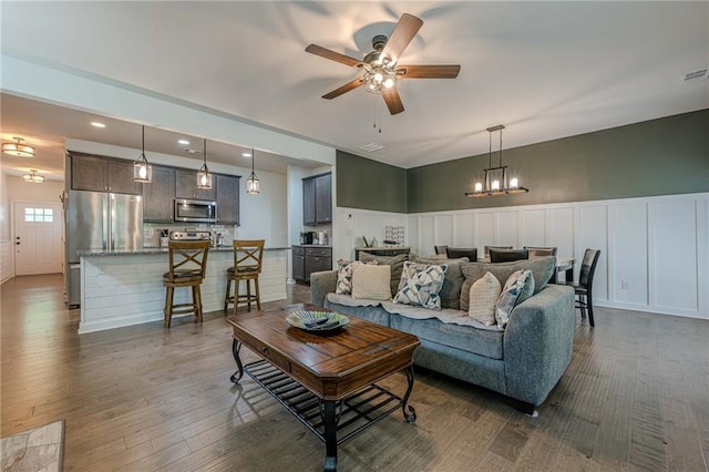 3291 Wild Basil Ln, Buford, GA 30519 - living room featuring a ceiling fan, a decorative wall, dark wood-type flooring, a wainscoted wall, and a chandelier