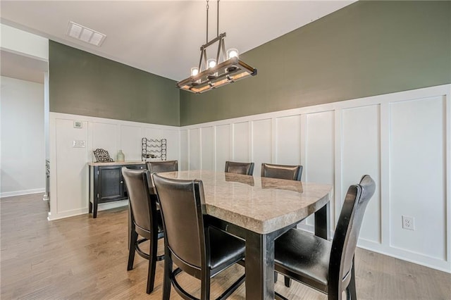 3291 Wild Basil Ln, Buford, GA 30519 - dining area with a decorative wall, light wood-style floors, wainscoting, and a chandelier