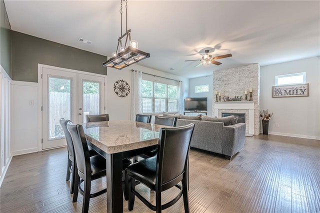 3291 Wild Basil Ln, Buford, GA 30519 - dining space featuring french doors, ceiling fan, wood finished floors, and a stone fireplace