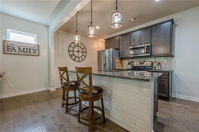 3291 Wild Basil Ln, Buford, GA 30519 - kitchen with appliances with stainless steel finishes, dark wood finished floors, dark stone countertops, and backsplash