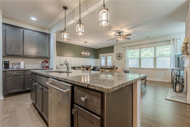 3291 Wild Basil Ln, Buford, GA 30519 - kitchen featuring stainless steel dishwasher, ceiling fan, light stone counters, a center island with sink, and pendant lighting
