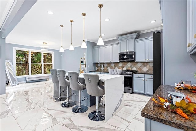 kitchen featuring appliances with stainless steel finishes, pendant lighting, an island with sink, dark stone countertops, and backsplash