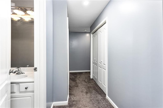 corridor with sink and dark carpet