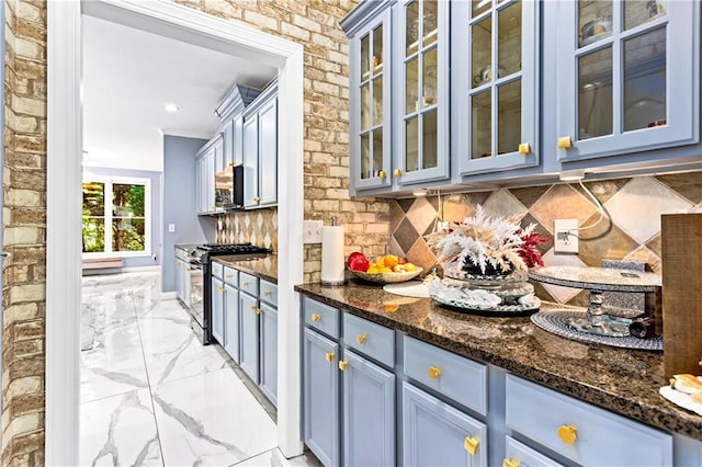 kitchen featuring brick wall, tasteful backsplash, dark stone counters, stainless steel appliances, and blue cabinetry