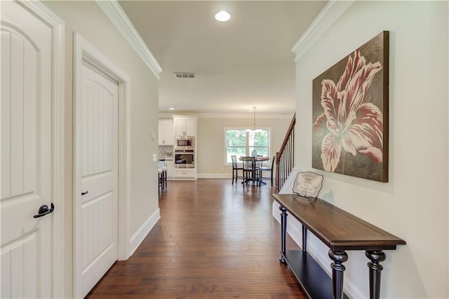 corridor featuring dark hardwood / wood-style flooring, crown molding, and a chandelier