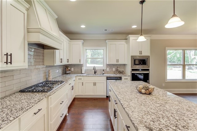 kitchen featuring appliances with stainless steel finishes, sink, light stone counters, and decorative light fixtures