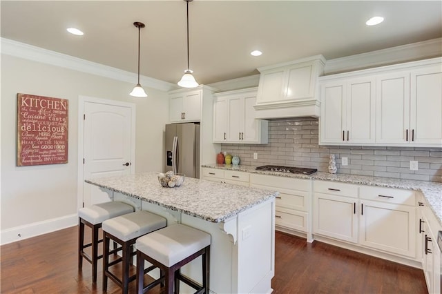 kitchen featuring white cabinetry, a center island, custom range hood, stainless steel appliances, and light stone countertops