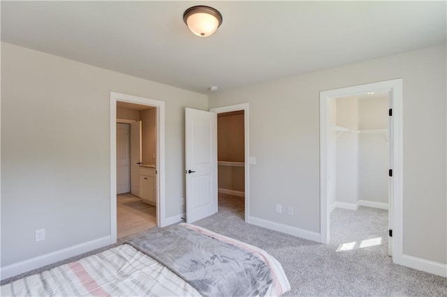 carpeted bedroom featuring a walk in closet, a closet, and ensuite bathroom