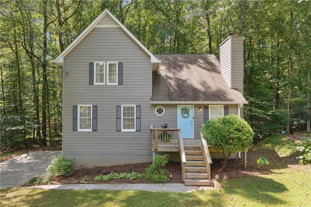 view of front of property featuring stairway, a chimney, and a wooded view