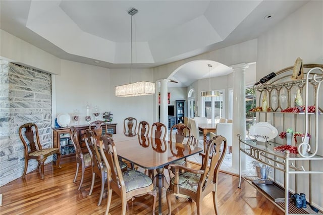 2935 Thompson Mill Rd, Gainesville, GA 30506 - dining area featuring ornate columns, arched walkways, a tray ceiling, and wood finished floors