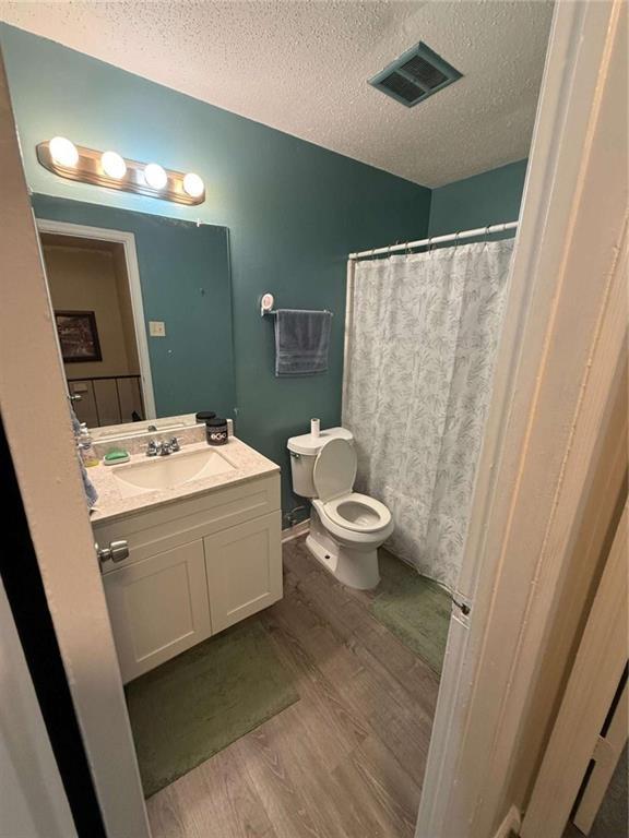 bathroom featuring vanity, toilet, hardwood / wood-style floors, and a textured ceiling