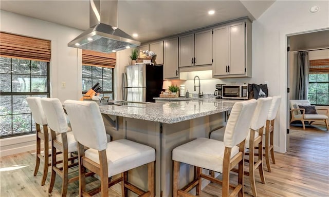 kitchen with island range hood, stainless steel appliances, gray cabinets, and light hardwood / wood-style flooring