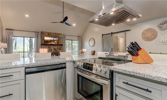 kitchen with stainless steel appliances, a barn door, white cabinets, and range hood