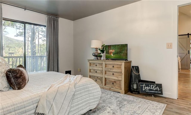 bedroom featuring a barn door and light wood-type flooring