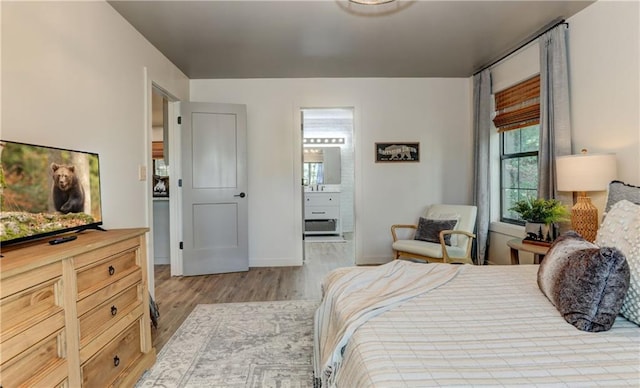 bedroom with light wood-type flooring and ensuite bath