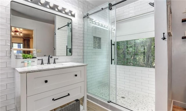 bathroom featuring vanity, a shower with shower door, and tile walls