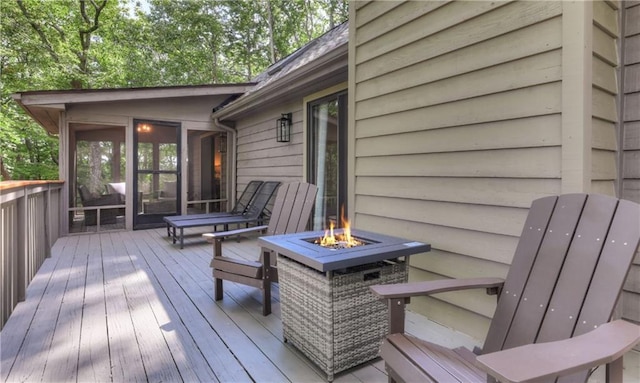 wooden deck featuring a fire pit and a sunroom