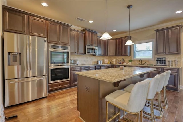 200 Baumgard, Locust Grove, GA 30248 - kitchen with stainless steel appliances, a center island, light stone counters, light wood-style floors, and dark brown cabinets