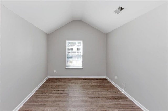 empty room with hardwood / wood-style flooring and vaulted ceiling