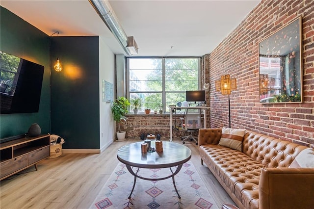 living room featuring light wood-type flooring, floor to ceiling windows, and brick wall