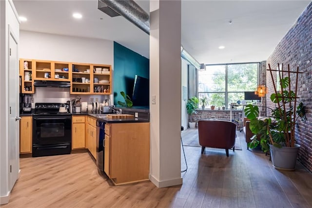 kitchen with black appliances, light hardwood / wood-style floors, sink, and brick wall